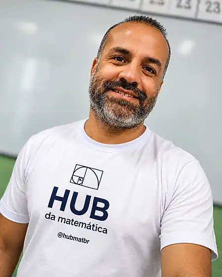 Professor Hélio Junior em uma sala de aula, com a camiseta do HUB da Matemática